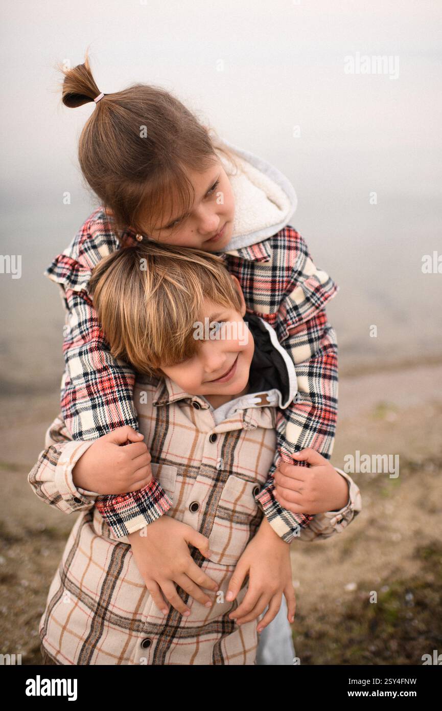 Bruder und Schwester umarmen sich am Strand nahe am Meer Stockfoto