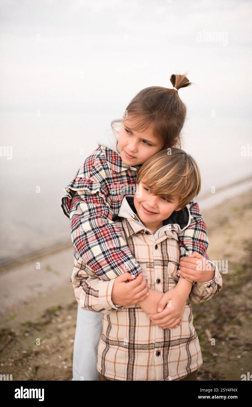 Bruder und Schwester umarmen sich am Strand nahe am Meer Stockfoto