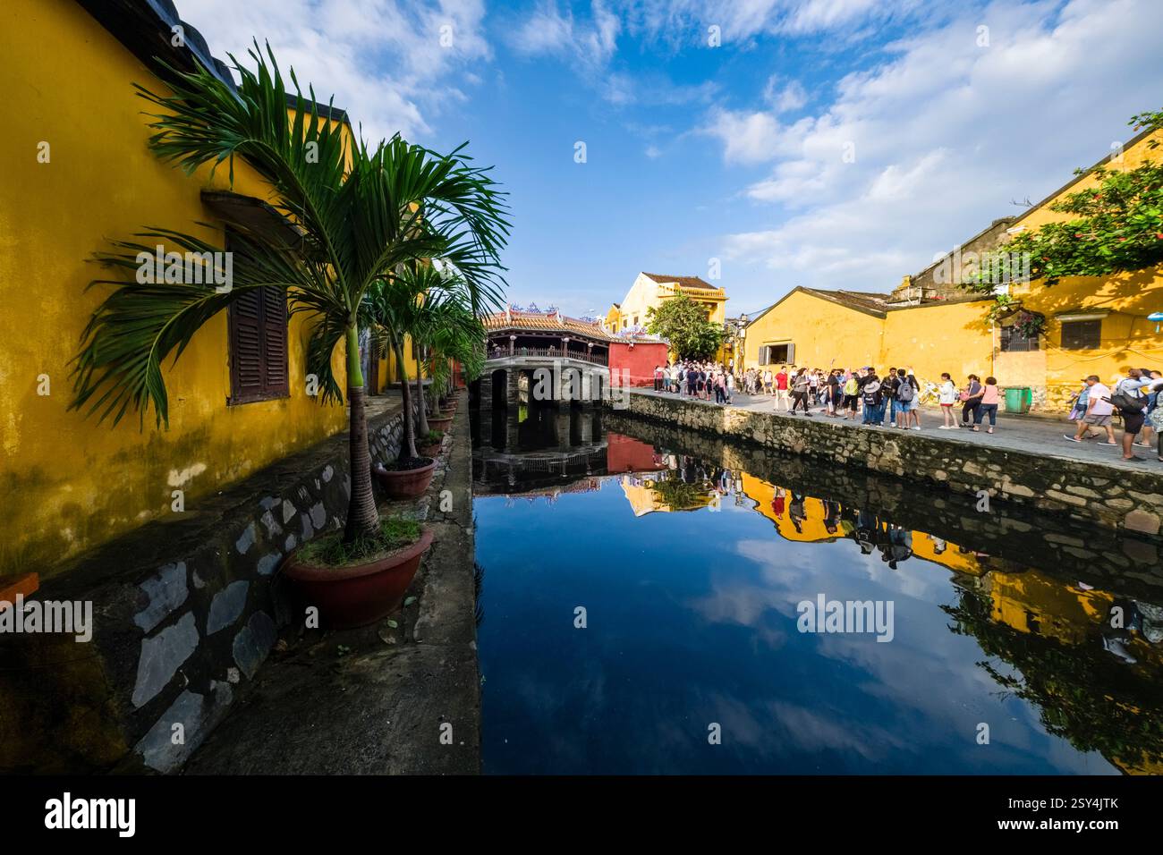 Touristen besuchen die Japanische Brücke, Chùa Cầu, die Pagode Brücke, eine Fußgängerbrücke mit einem kleinen Tempel auf der Spitze, der sich in einem Wasserkanal spiegelt Stockfoto