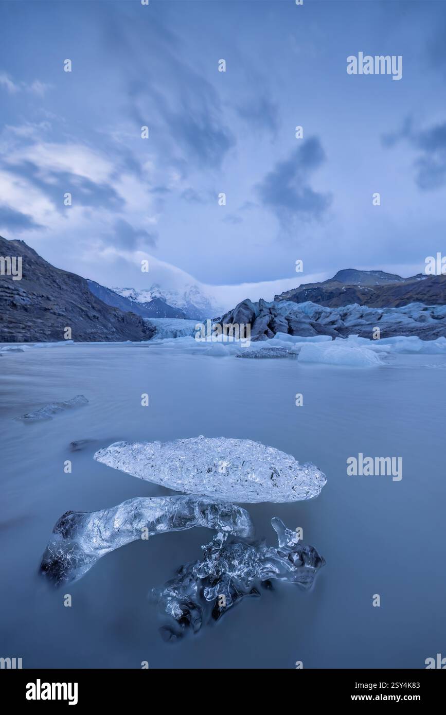 Schmelzendes Eis auf einem Gletschersee mit Gletscher und Bergen im Hintergrund aufgrund der globalen Erwärmung und des Klimawandels. Stockfoto