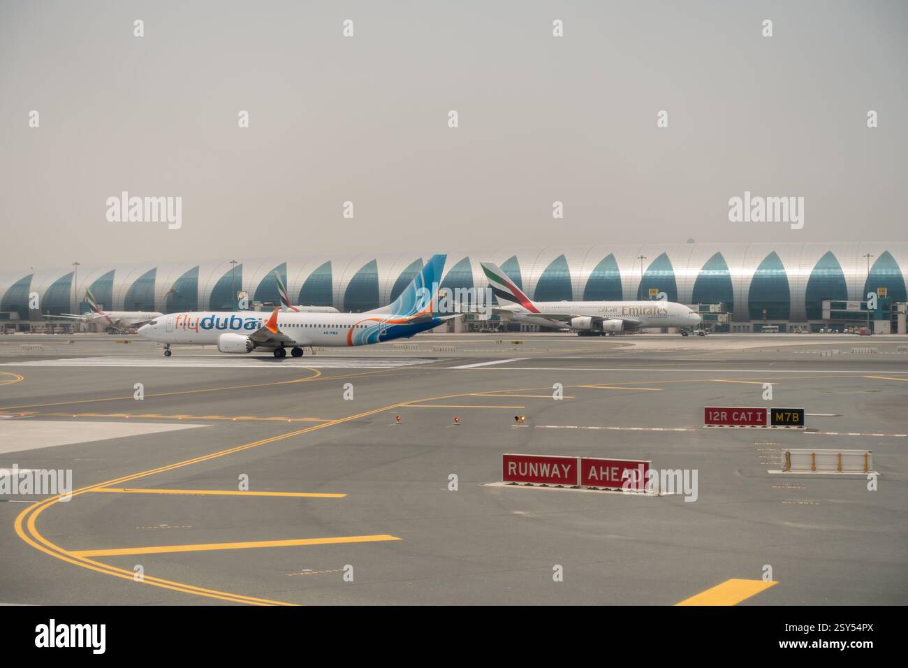 Dubai, Vereinigte Arabische Emirate - 16. Juli 2024: Dubais Flaggschiff Flydubai und ein Emirates a380 Flugzeug auf dem Asphalt der Dubai International Stockfoto