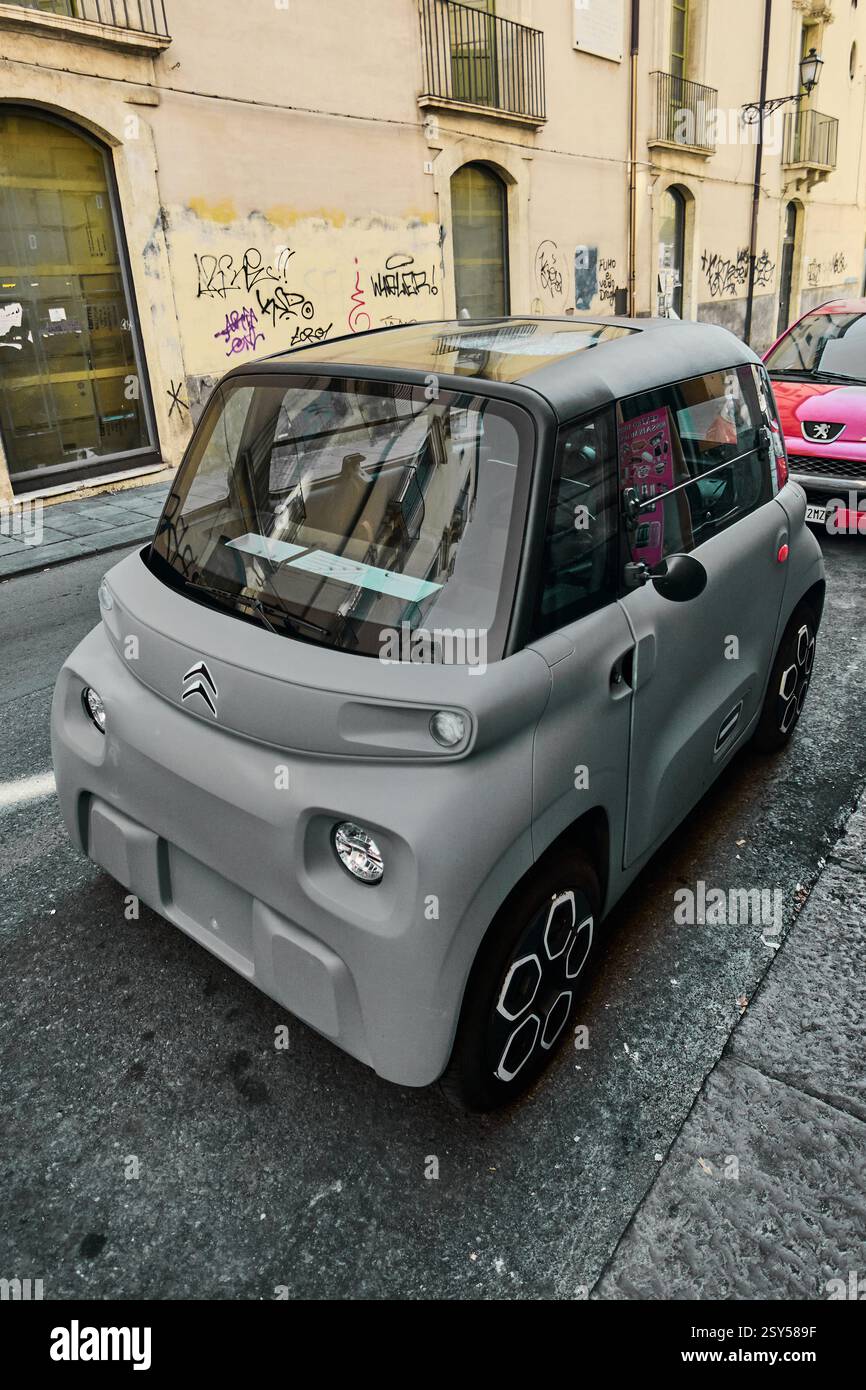 Catania. Italien - 27. Februar 2025: Elegantes graues Citroen Ami Elektrovierrad parkt auf einer Straße in Catania, umgeben von Graffiti-bedeckten Gebäuden u Stockfoto