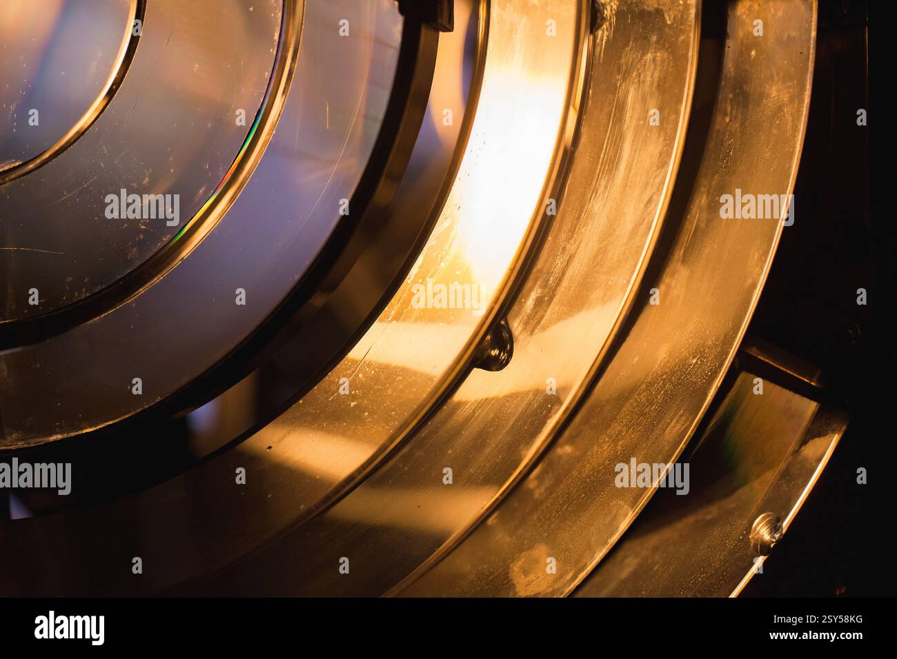 Abstrakte Nahaufnahme einer hellen, beleuchteten Fresnel-Linse mit leuchtenden Reflexionen auf dunklem Hintergrund, die komplizierte Details in der Desi zeigt Stockfoto