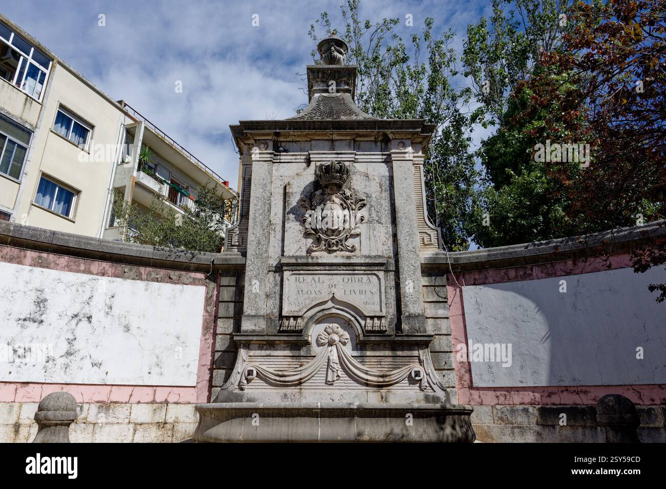 Ein kunstvoll verziertes historisches Steindenkmal mit königlichem Wappen und Inschrift vor einem modernen Gebäude Stockfoto