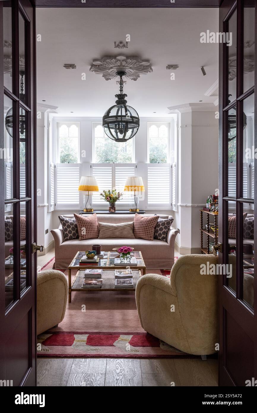 Sessel mit neuseeländischem Lammfell und Deckenhöhe über den Sitzgelegenheiten in zeitgenössischem Neudesign eines Hauses in West London. Stockfoto