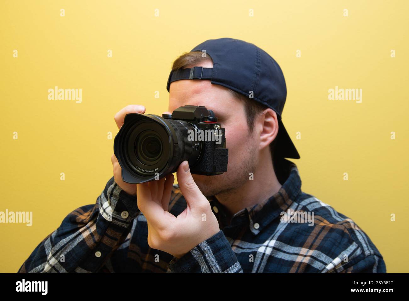 Ein männlicher Fotograf, der gerade fotografiert, auf gelbem Hintergrund. Stockfoto