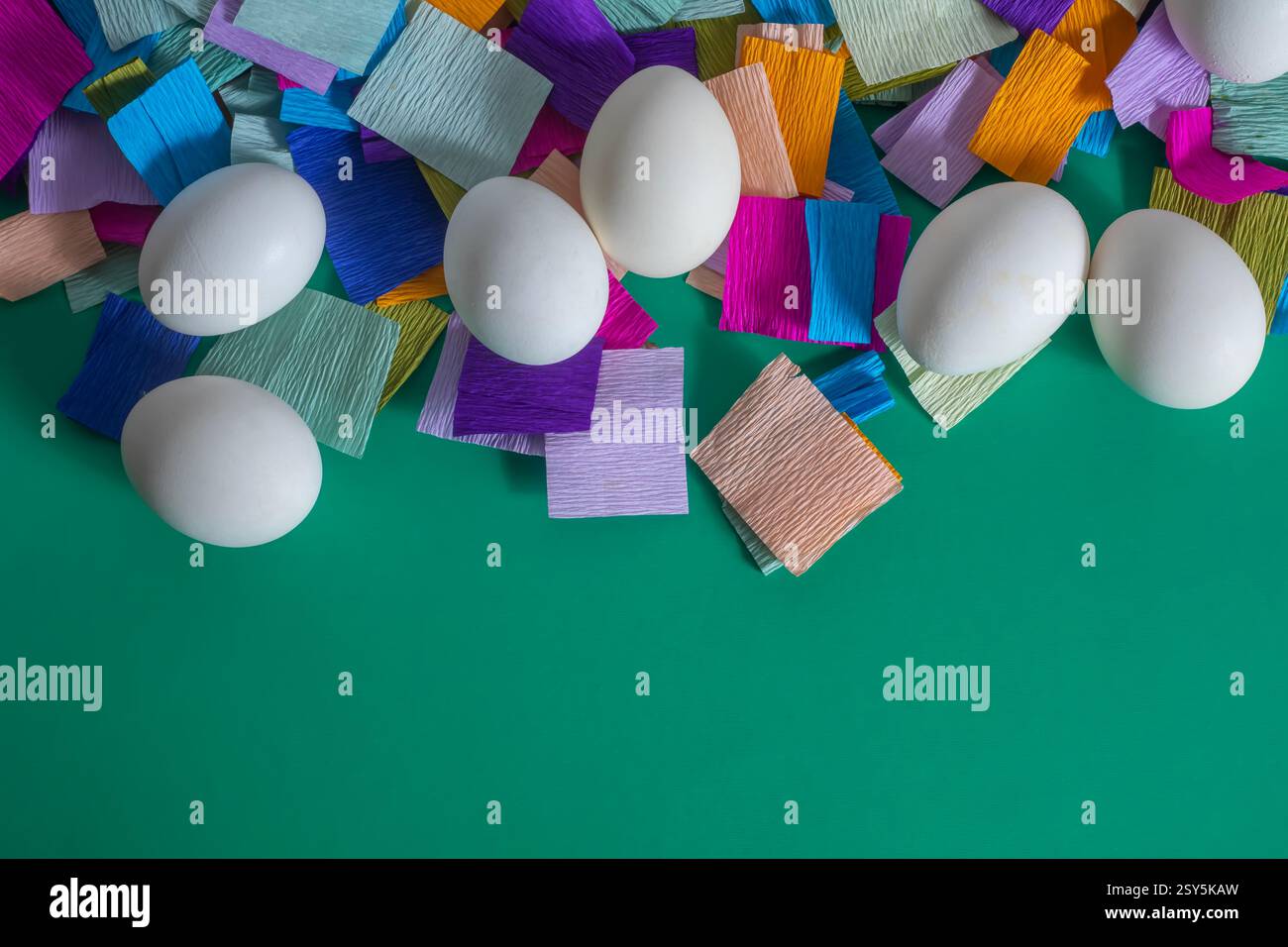Blick von oben auf hell dekorierte Ostereier auf einem mehrfarbigen Krepppapierhintergrund. Stockfoto