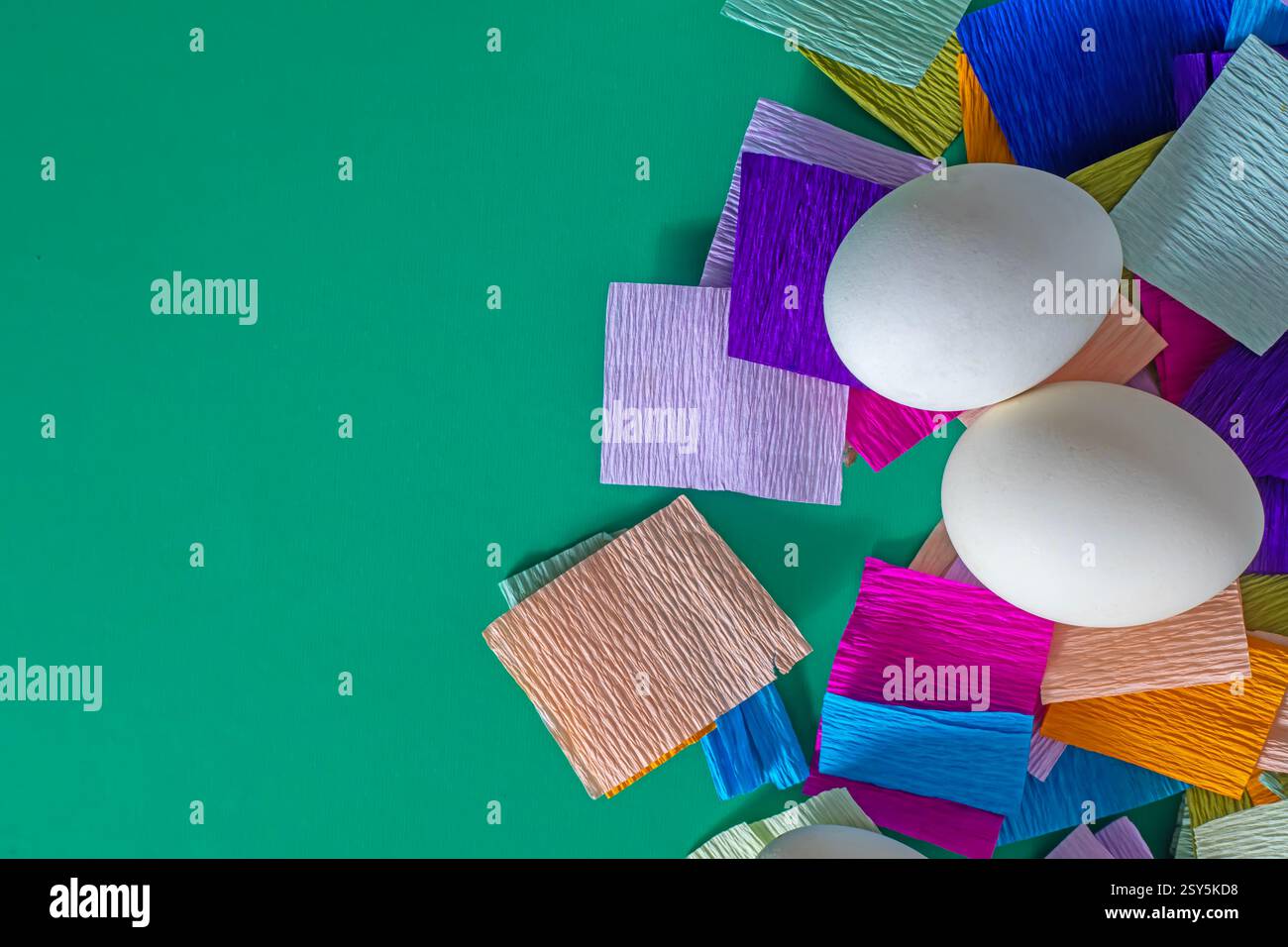 Draufsicht auf weiße Eier mit farbigem Papier auf grünem Hintergrund. Frohe Ostern. Stockfoto