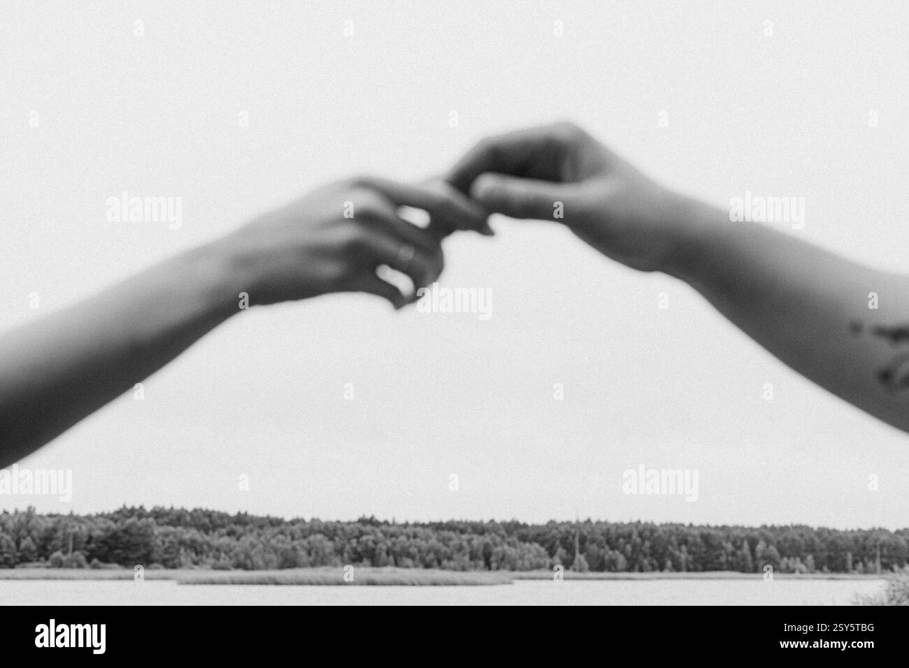 Romantisches Paar, das sich an einem bewölkten Tag in der Nähe eines Sees und eines Waldes küsst und umgibt. Stockfoto