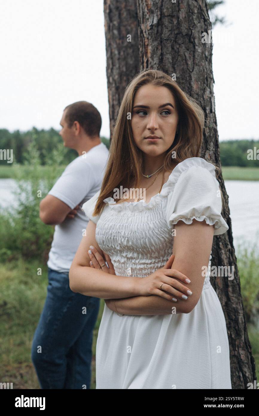 Romantisches Paar, das sich an einem bewölkten Tag in der Nähe eines Sees und eines Waldes küsst und umgibt. Stockfoto
