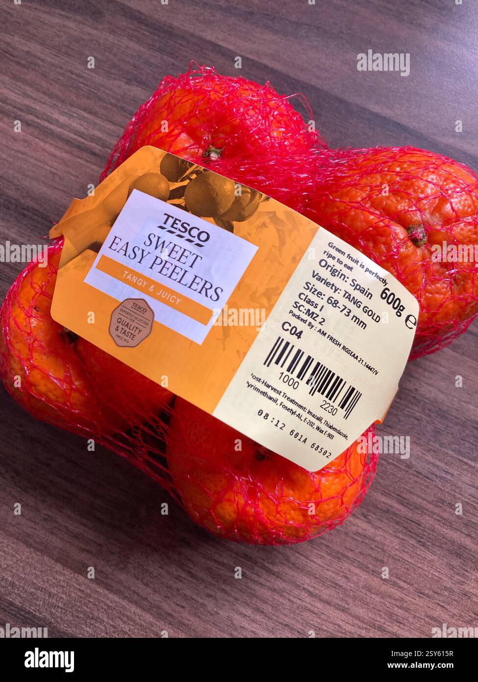 Packung mit vier Mandarinen-Früchten in Tesco Supermarkt-Netztasche auf Holztisch mit Kopierraum - Smartphone-aufgenommenes Stockfoto