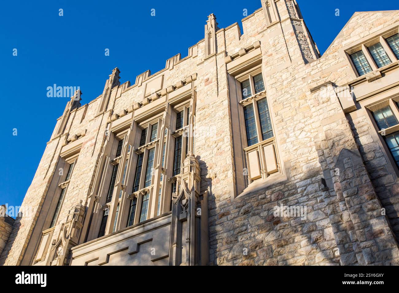 Großes Gebäude mit einer Steinfassade und einem blauen Himmel im Hintergrund. Das Gebäude hat viele Fenster und einen Uhrenturm Stockfoto
