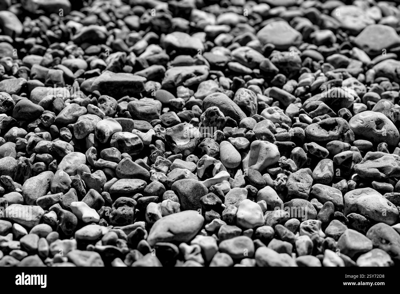 Schwarzweißbild von Steinen und Kieselsteinen am Strand; zufällige Texturen und Muster im Chaos von Dunraven Bay an der Glamorgan Heritage Coast Stockfoto