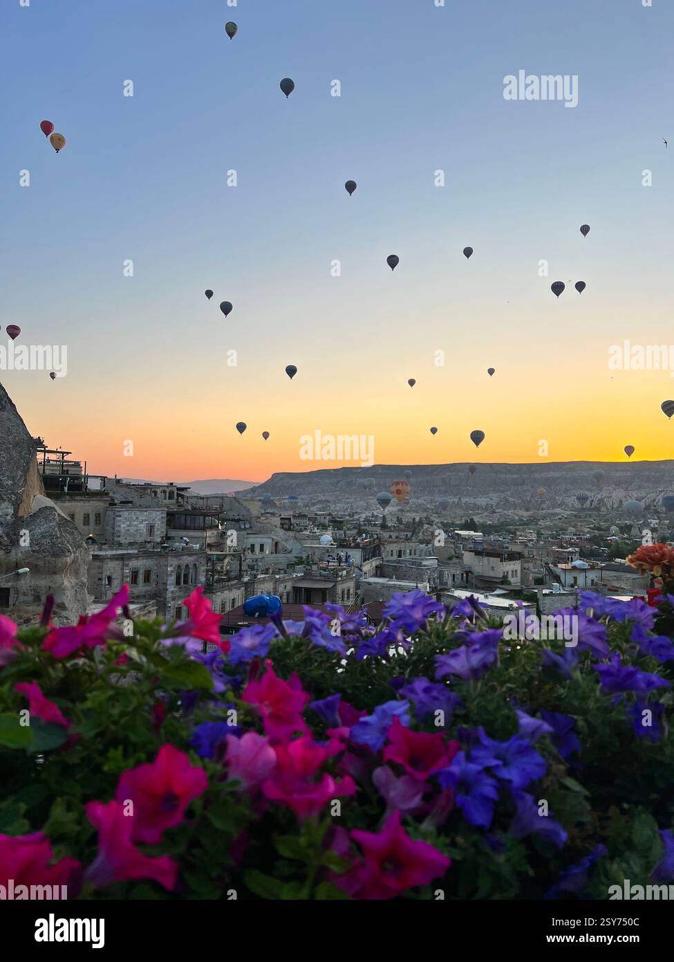 Farbenfrohe Heißluftballons schweben bei Sonnenaufgang über Kappadokiens Felsformationen Stockfoto