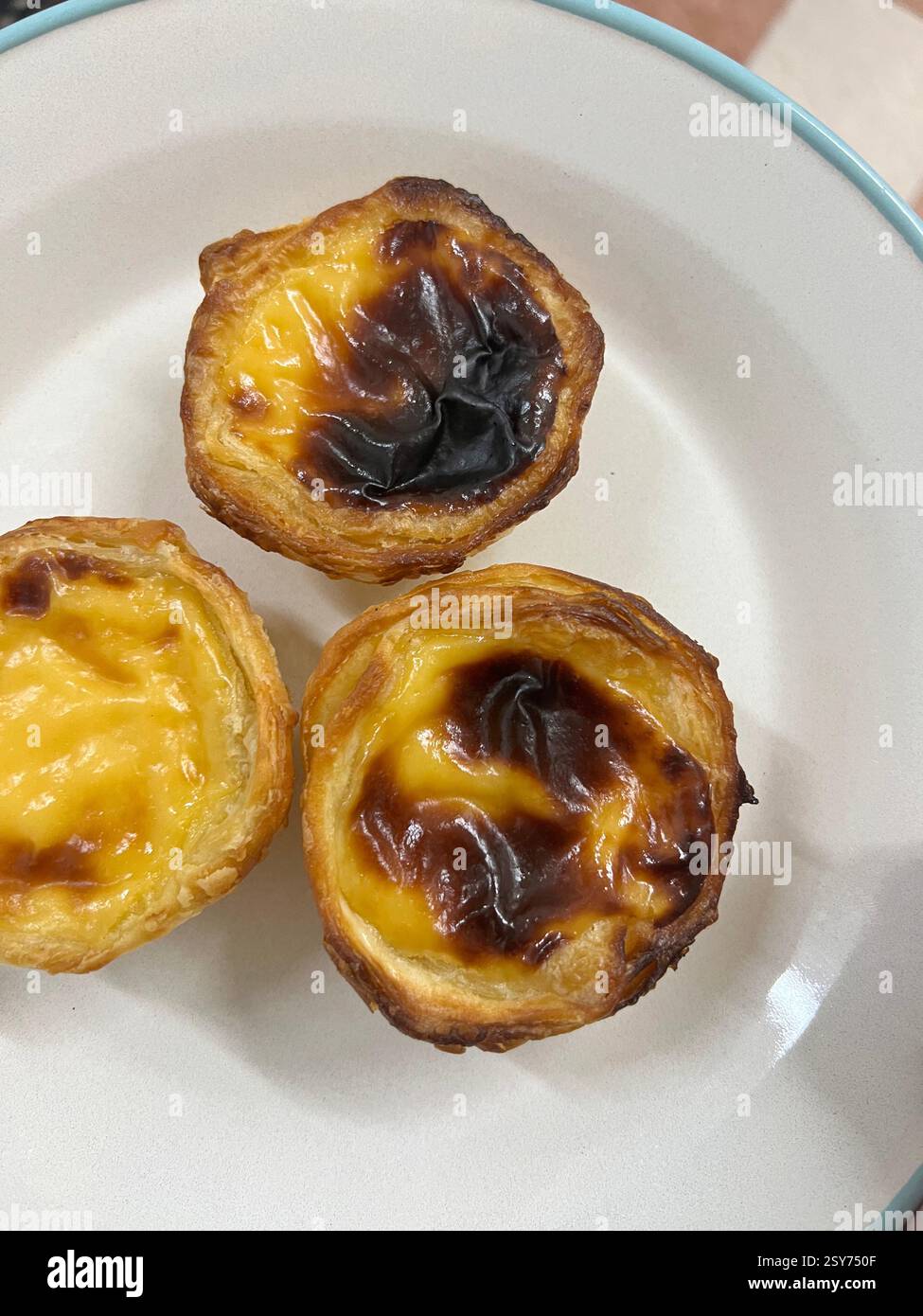 Drei frisch gebackene portugiesische Puddingkuchen mit knusprigen Krusten und karamellisierten Tops. Stockfoto