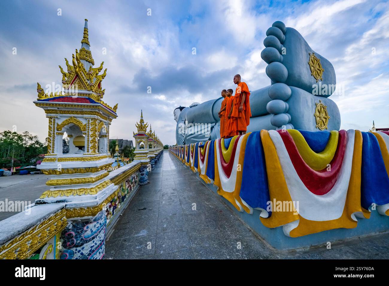 Drei buddhistische Mönche stehen vor der 63 Meter langen Statue eines liegenden Buddha in der Som Rong-Pagode, Chùa Som Rong, einem berühmten spirituellen Ort Stockfoto