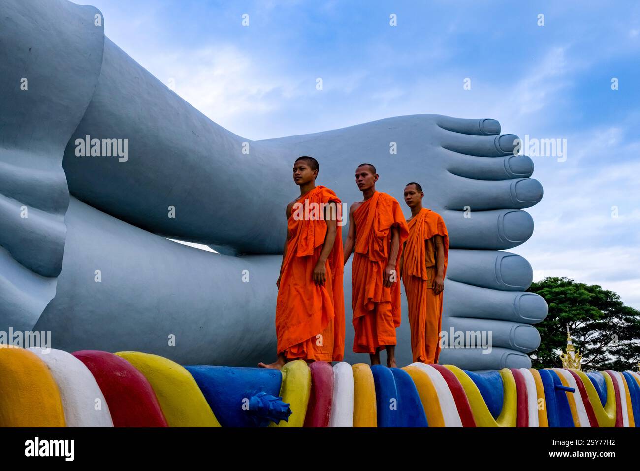 Drei buddhistische Mönche spazieren vor der 63 Meter langen Statue eines liegenden Buddha in der Som Rong-Pagode, Chùa Som Rong, einem berühmten spirituellen Ort i Stockfoto