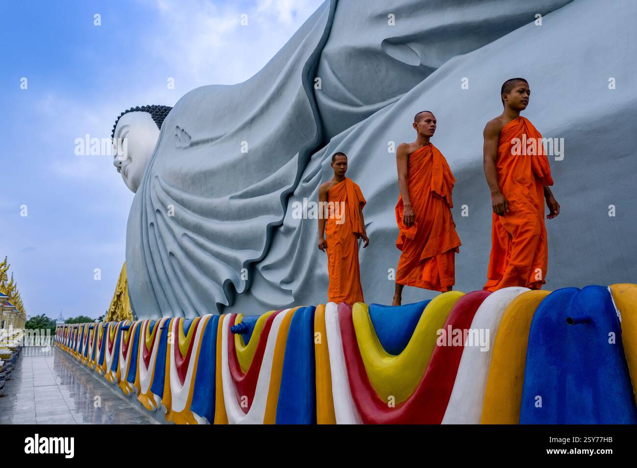 Drei buddhistische Mönche spazieren vor der 63 Meter langen Statue eines liegenden Buddha in der Som Rong-Pagode, Chùa Som Rong, einem berühmten spirituellen Ort i Stockfoto
