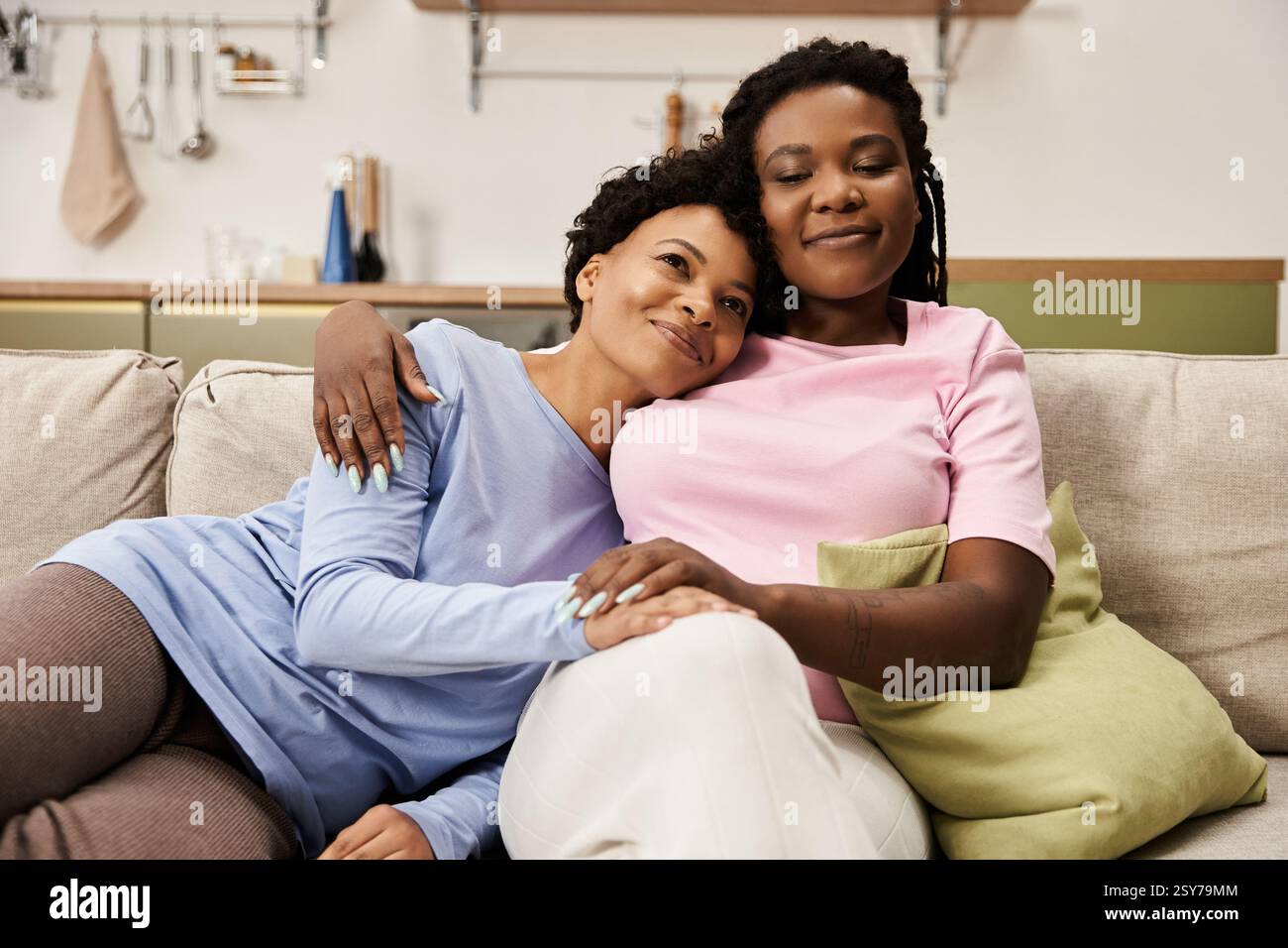 Zwei liebevolle Frauen teilen sich einen zärtlichen Moment auf einer gemütlichen Couch zu Hause. Stockfoto