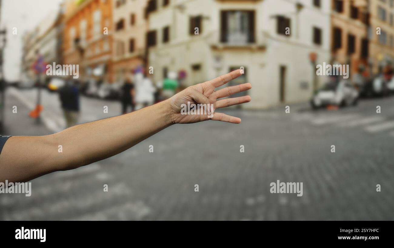 Mann draußen, der vier Finger hoch hält auf einer belebten Straße mit Gebäuden und Menschen im Hintergrund. Stockfoto