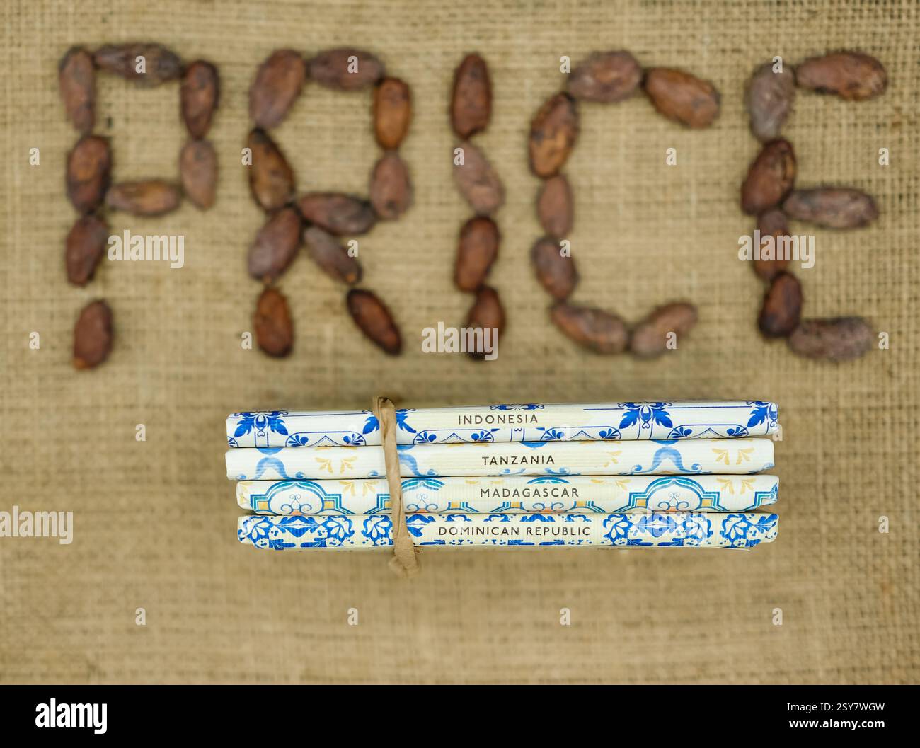 Die Terroir-Schokoladentafeln aus Indonesien, Tansania, Madagaskar und der Dominikanischen Republik sind auf dem unscharfen Wort Preis aus Kakaobohnen. Jute-Sack zurück. Stockfoto