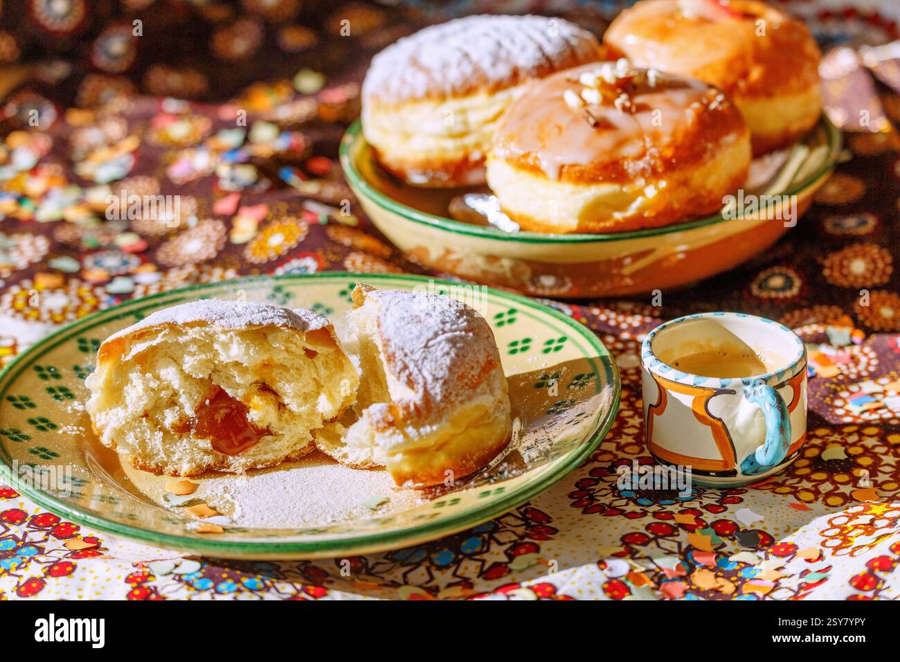 mit Marillenmarmelade gefüllter Faschingskrapfen mit Puderzucker, in der Mitte zerteilen, Keramikteller weiß-grün melliert, Espressotasse, Keramikschal Stockfoto