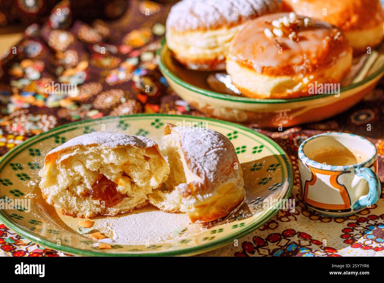 mit Marillenmarmelade gefüllter Faschingskrapfen mit Puderzucker, in der Mitte zerteilen, Keramikteller weiß-grün melliert, Espressotasse, Keramikschal Stockfoto