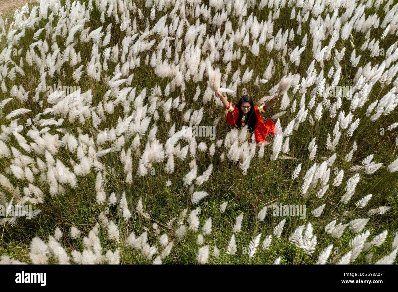 Eine fröhliche junge Frau genießt die Schönheit der blühenden Kans-Grasblumen, die das Wesen des Herbstes am Stadtrand von Dhaka, Bangladesch, genießen. Stockfoto