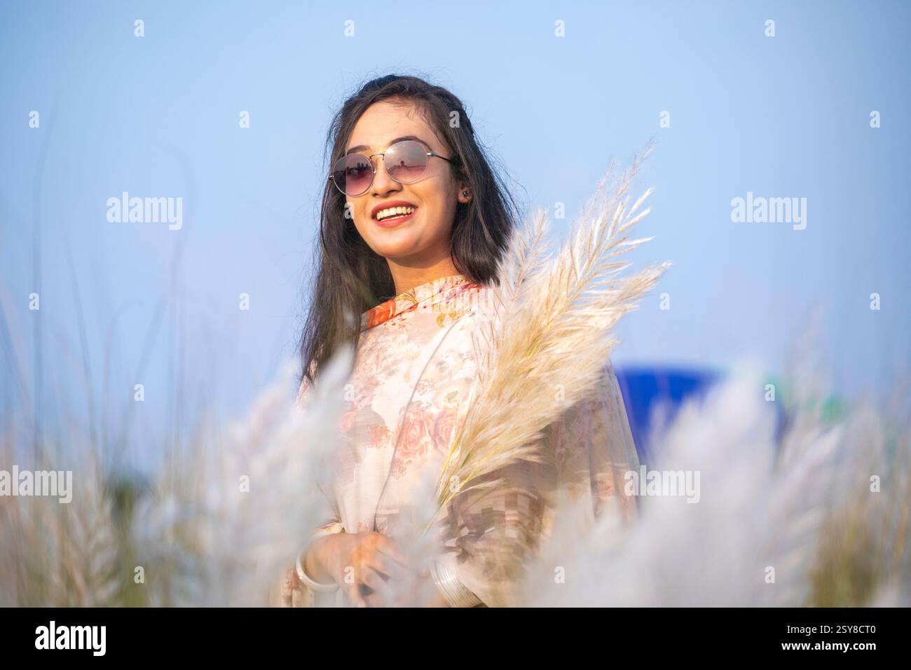 Eine fröhliche junge Frau genießt die Schönheit der blühenden Kans-Grasblumen, die das Wesen des Herbstes am Stadtrand von Dhaka, Bangladesch, genießen. Stockfoto