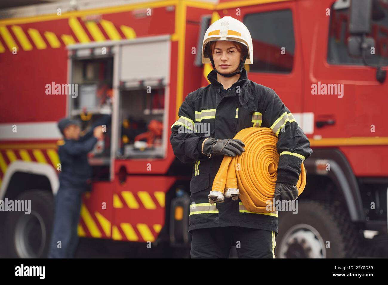 Halten des Feuerwehrschlauchs. Frau in Uniform arbeitet in der Abteilung. Stockfoto