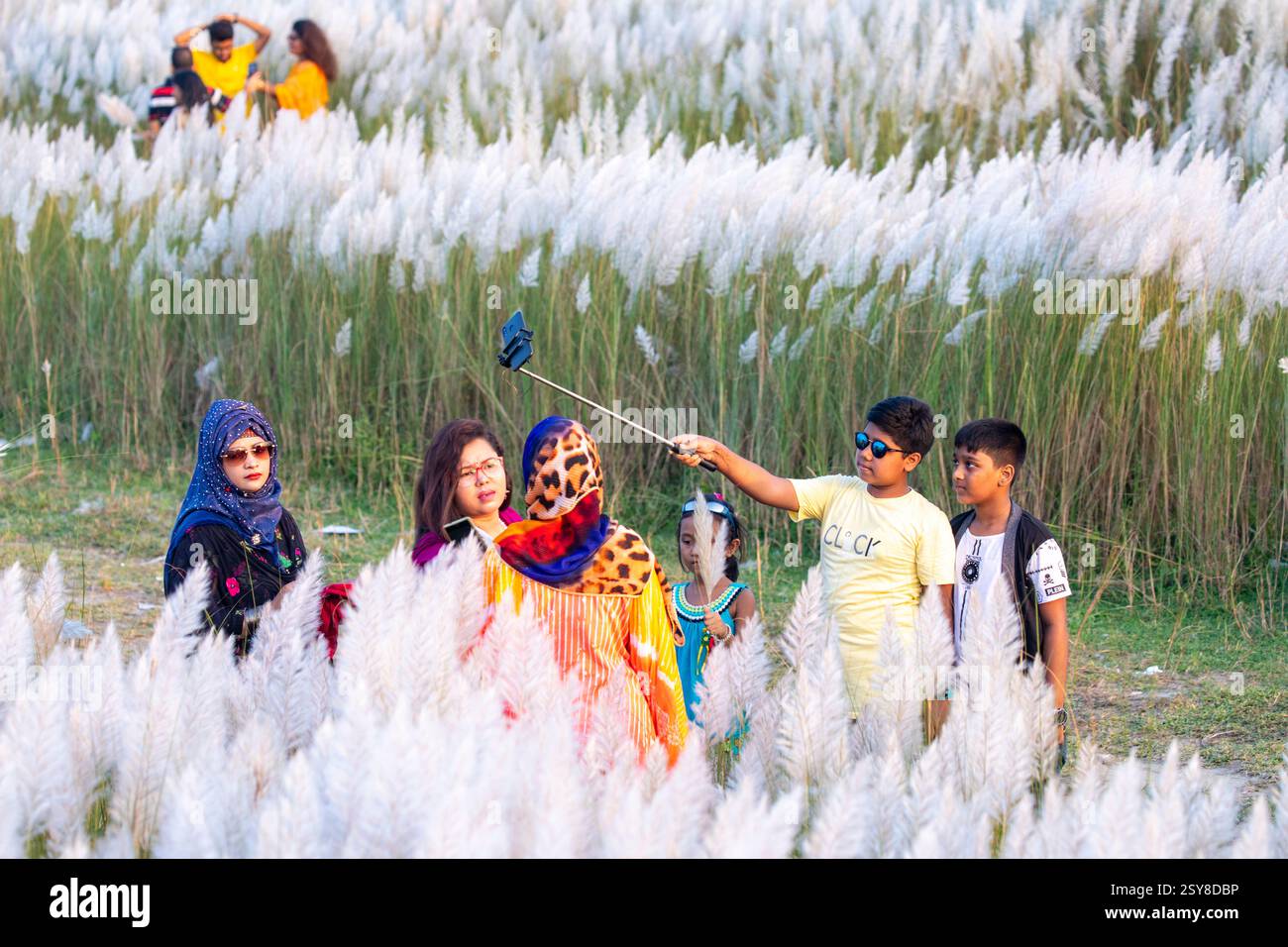 Die Menschen tauchen ein in die Schönheit der blühenden Kans-Grasblumen und feiern das Wesen des Herbstes am Stadtrand von Dhaka, Bangladesch. Stockfoto