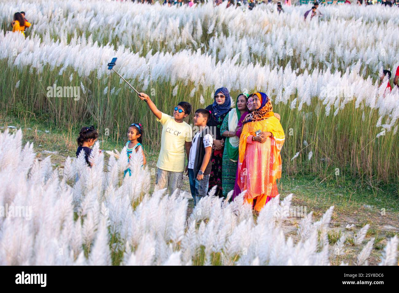 Die Menschen tauchen ein in die Schönheit der blühenden Kans-Grasblumen und feiern das Wesen des Herbstes am Stadtrand von Dhaka, Bangladesch. Stockfoto