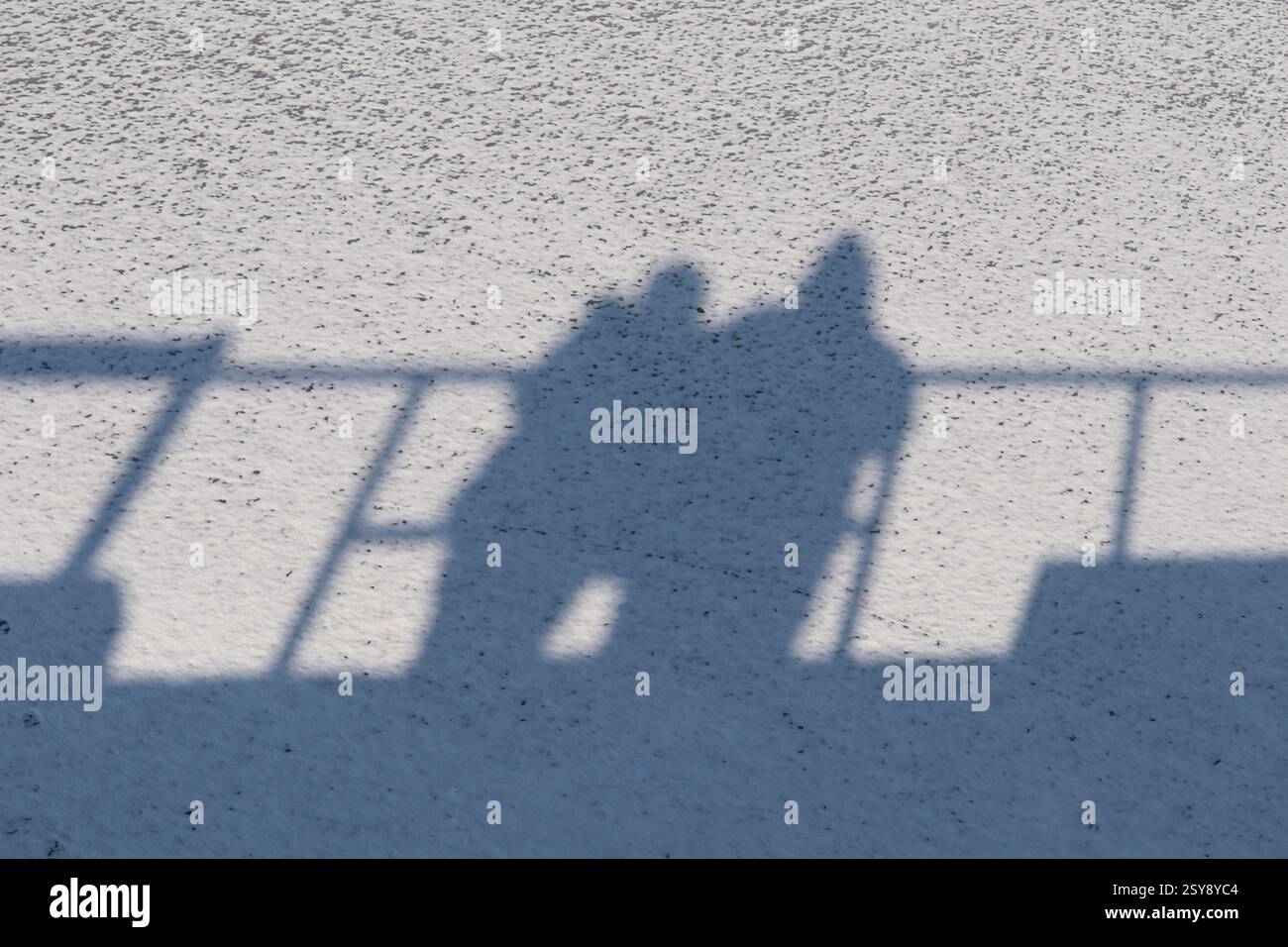 Die Schatten eines Mannes und einer Frau sind auf dem Schnee sichtbar. Stockfoto