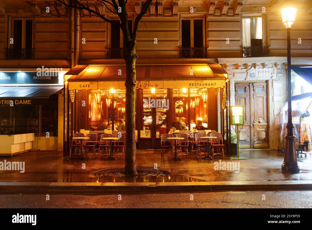 PARIS, Frankreich - 23. Februar 2025 : Blick auf das typische Pariser Restaurant Le Parvis bei regnerischer Nacht. Es liegt in der Nähe der Kathedrale Noter Dame in Paris, F Stockfoto