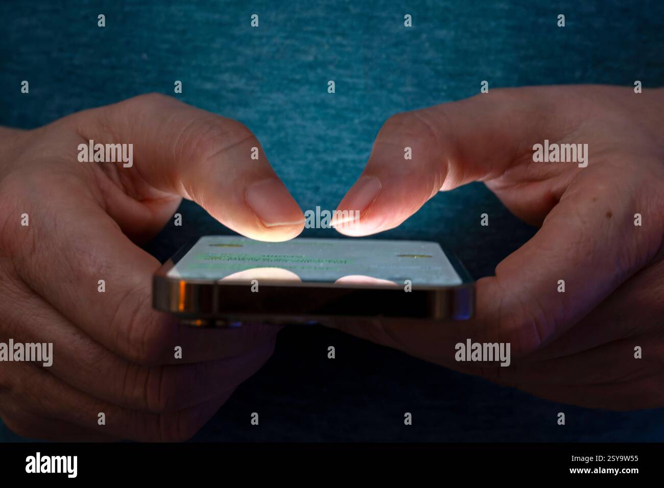 27.02.2025, Thema Smartphone-Nutzung, Frau tippt auf einem Apple iPhone13 Smartphone-Screen SMS. Das Bild zeigt eine Person, die in einer schlecht beleuchteten Umgebung ein Smartphone benutzt. Die Beleuchtung hebt die Finger des Benutzers und den Bildschirm des Smartphones hervor. 27.02.2025, Smartphone 27.02.2025, Smartphone *** 27 02 2025, Thema Smartphone-Nutzung, Frau, die auf einem Apple iPhone13 Smartphone-Bildschirm SMS tippt das Bild zeigt eine Person, die ein Smartphone in einer schlecht beleuchteten Umgebung verwendet. Die Beleuchtung hebt die Finger des Benutzers und den Smartphone-Bildschirm hervor 27 02 2025, Smartphone 27 02 2025, SMA Stockfoto