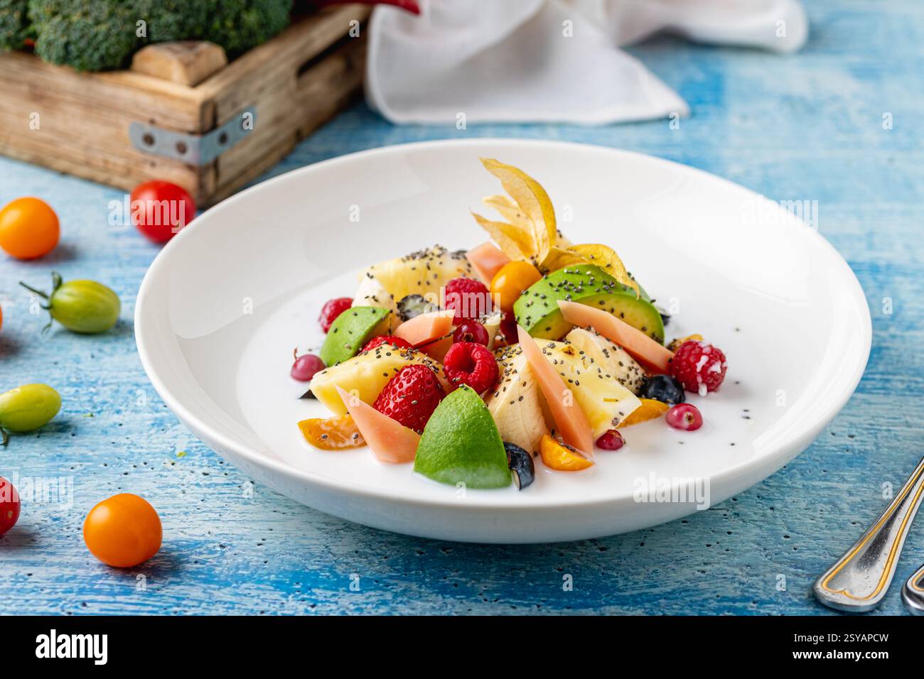 Gemischter Obstsalat mit Früchten wie Banane, Erdbeere und Ananas auf einer weißen Porzellanplatte Stockfoto