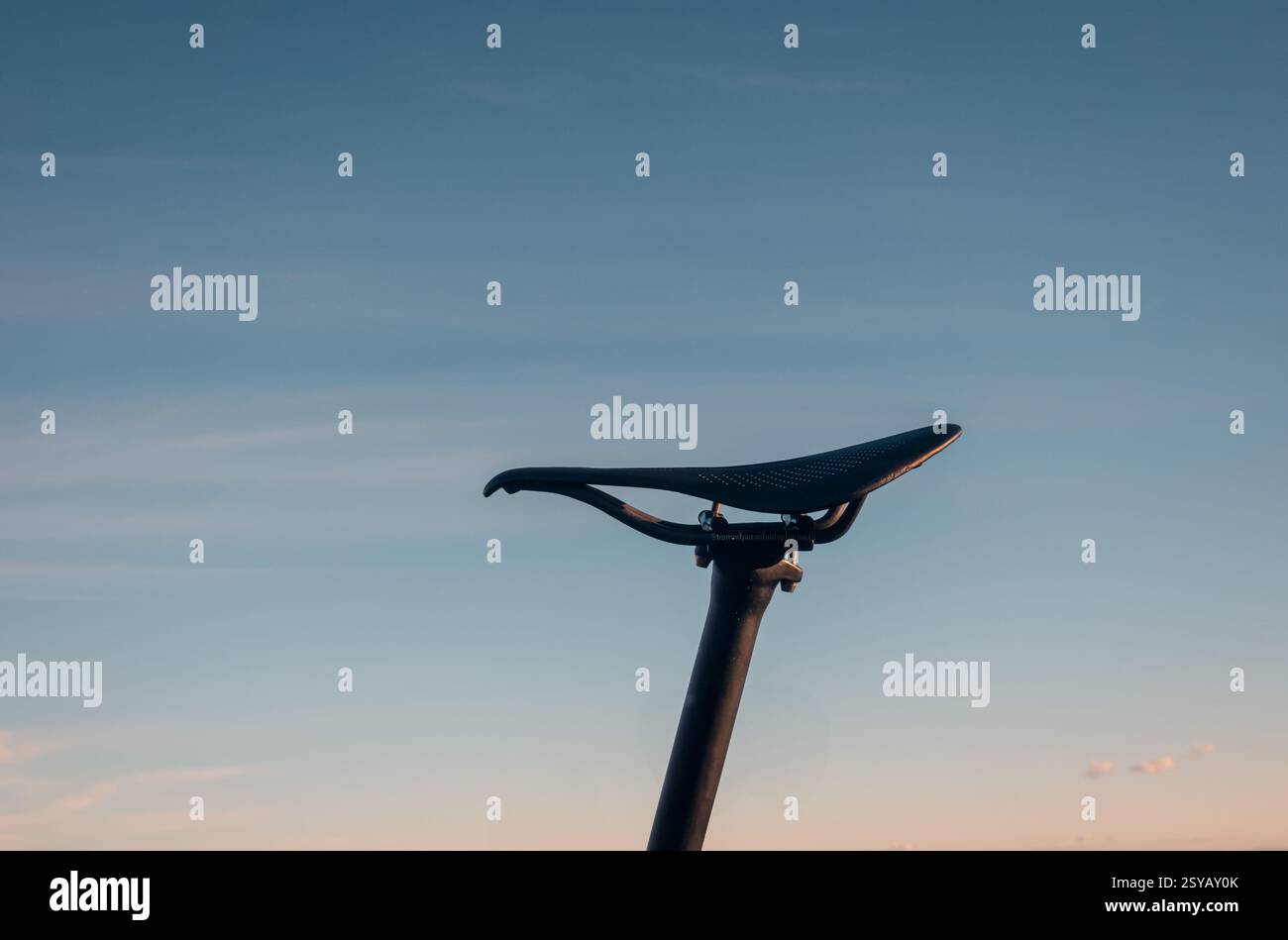 Eine minimalistische Silhouette eines Fahrradsattelsitzes vor einem weichen Himmel bei Sonnenuntergang. Das Bild weckt ein Gefühl von Frieden und Einsamkeit und fängt die Simplici ein Stockfoto