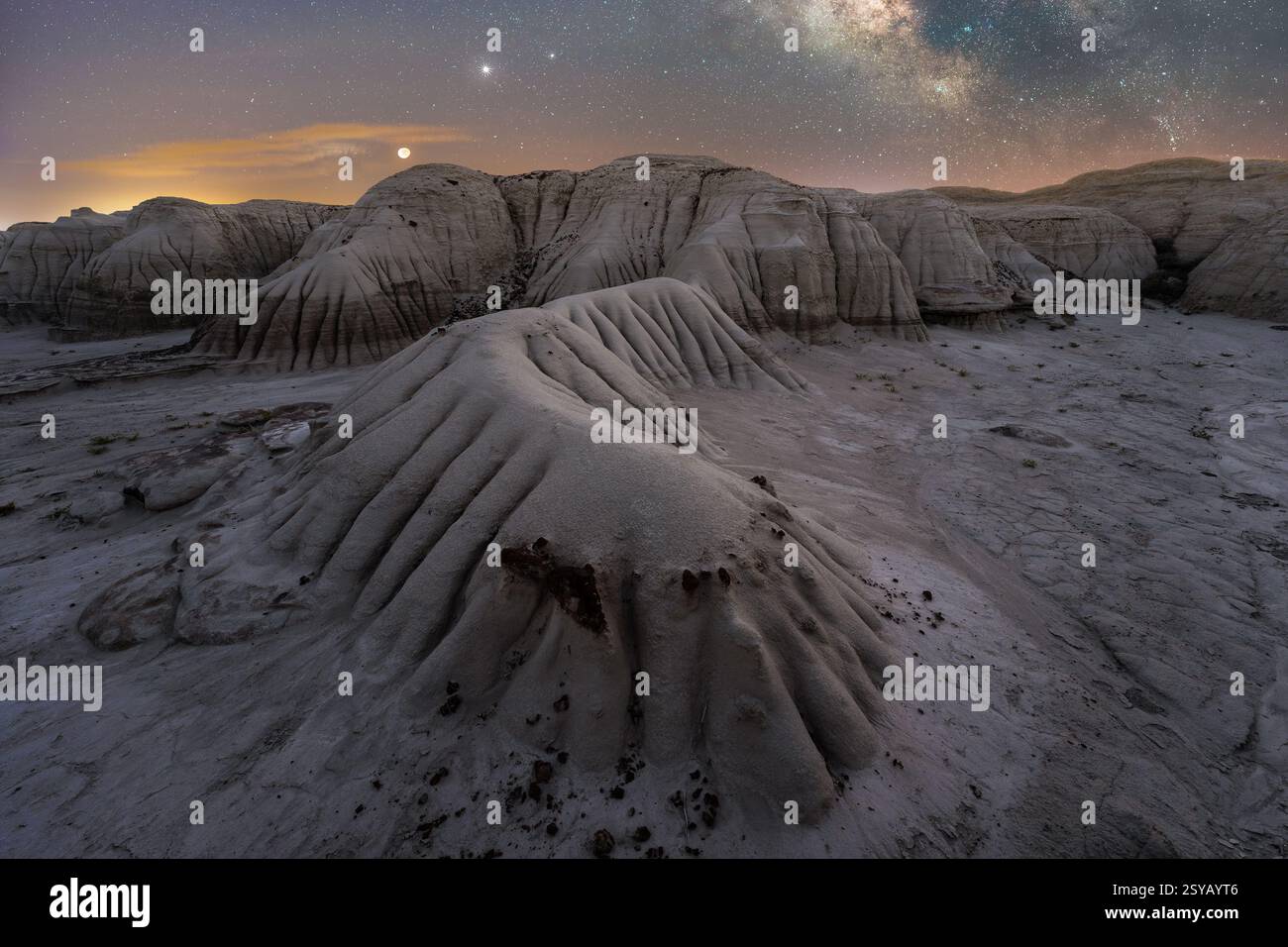 Eine ruhige nächtliche Szene fängt Utahs strukturierte Landschaft unter einem Sternenhimmel ein, der vom Mond und fernen Planeten hervorgehoben wird. Stockfoto