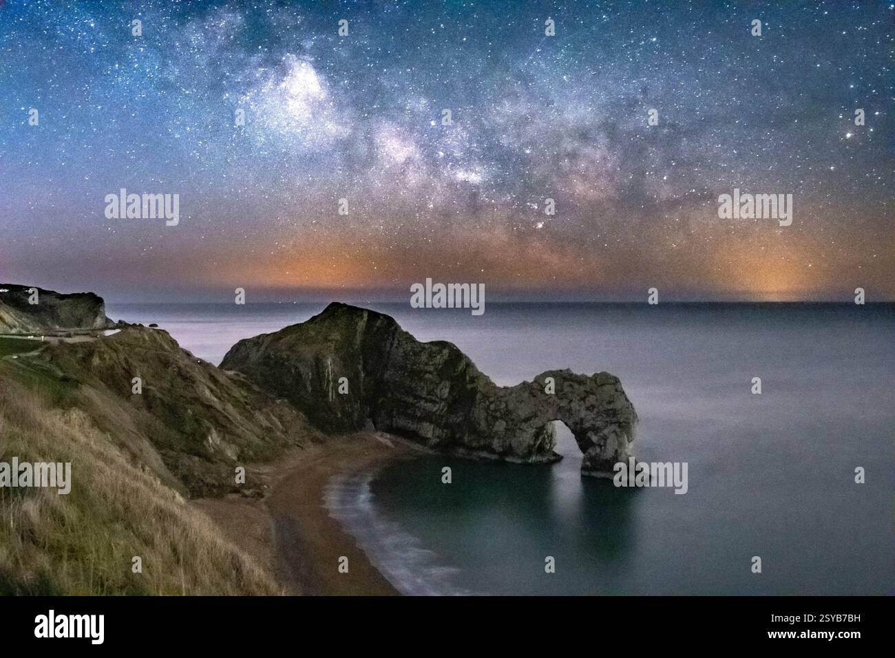 Durdle Door, Dorset, Großbritannien. Februar 2025. Wetter in Großbritannien. Der galaktische Kern der Milchstraße leuchtet am letzten Tag des meteorologischen Winters hell im klaren Winterhimmel über Durdle Door in Dorset Stockfoto