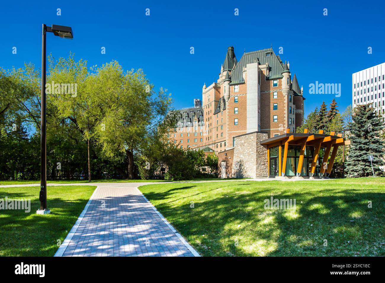 Der gemauerte Gehweg führt zu einem großen Gebäude. Das Gebäude hat einen großen Turm und ist von Bäumen umgeben Stockfoto