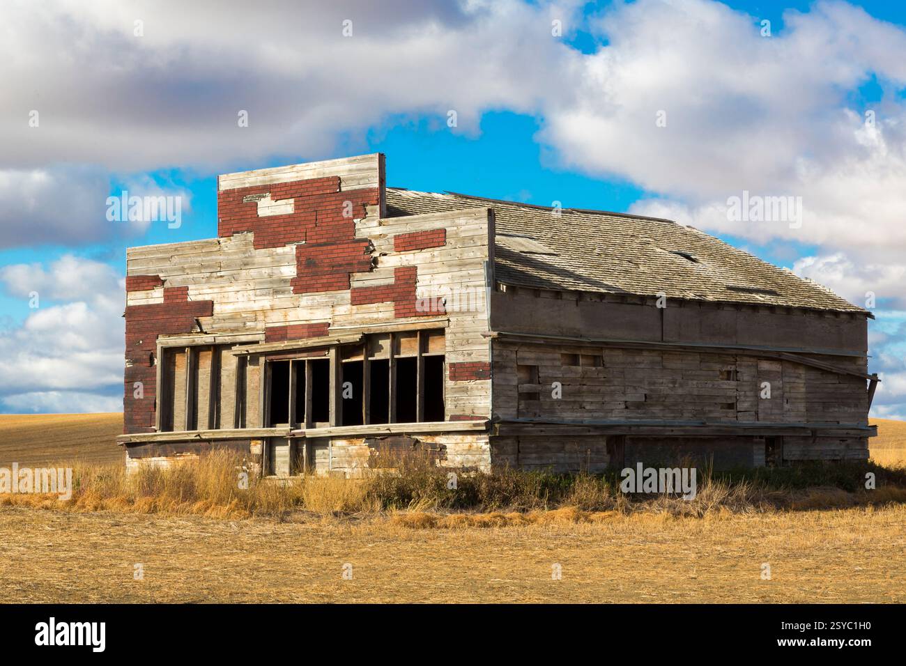 Gebäude mit roter Ziegelfassade und weißem Dach. Das Gebäude ist alt und hat viele Risse Stockfoto