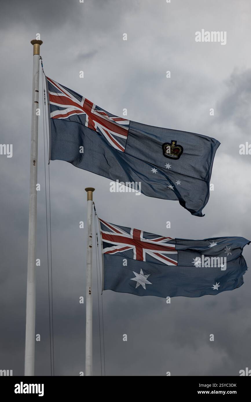 Viktorianischer Staat und australische Flaggen winken unter stürmischem Himmel Stockfoto
