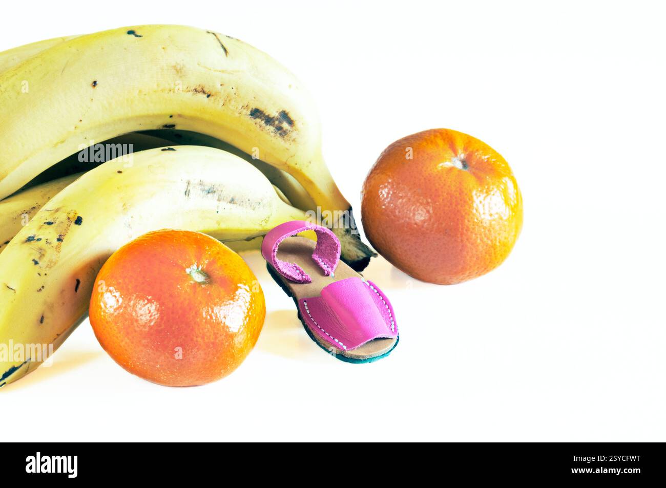 Stillleben von Bananen, eine Sommersandale und zwei Mandarinen aus dem Garten. Stockfoto