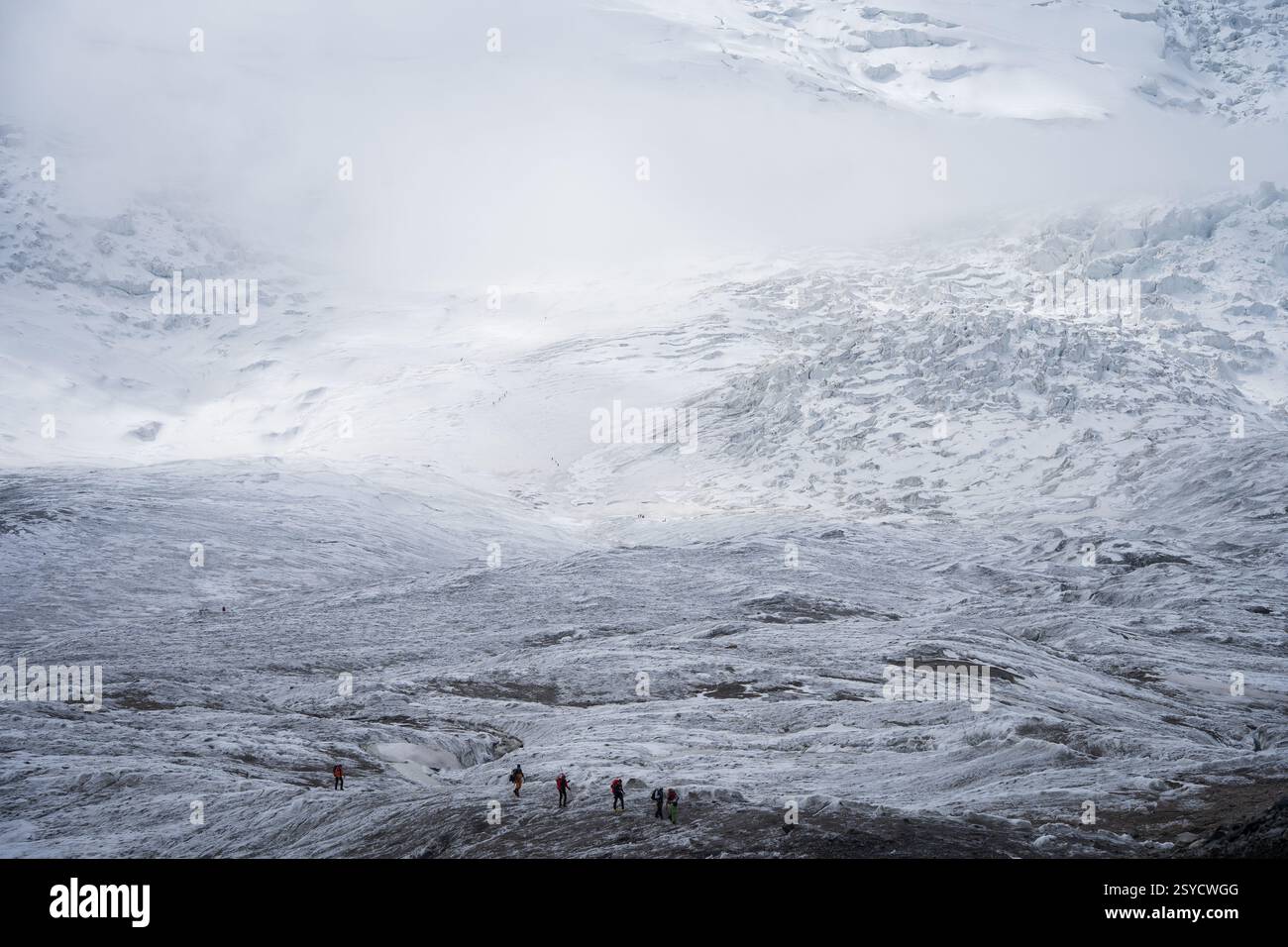 Gruppe von Menschen, die das weiße und schneebedeckte Gletschergelände durchqueren, Pamir Mountains, Kirgisistan Stockfoto