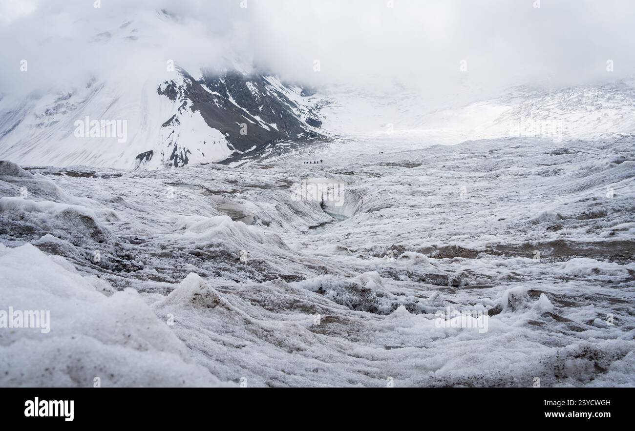 Blick auf das riesige Gletschergelände mit winzigen Gruppenmitgliedern, die es überqueren, Pamir Mountains, Kirgisistan Stockfoto