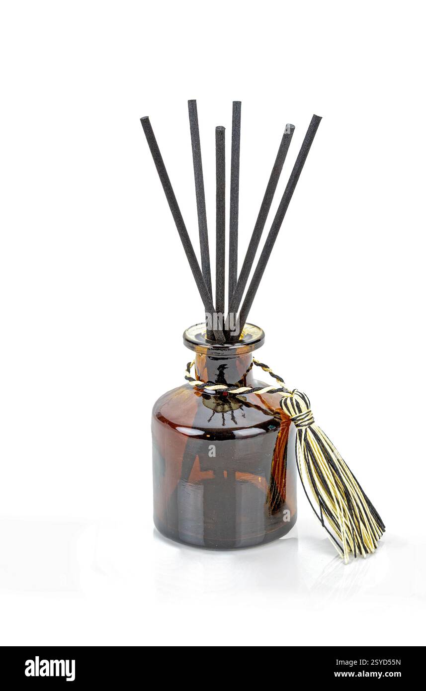 Schwarze Lufterfrischer werden in eine braune Parfümflasche aus Glas eingeführt. Stockfoto