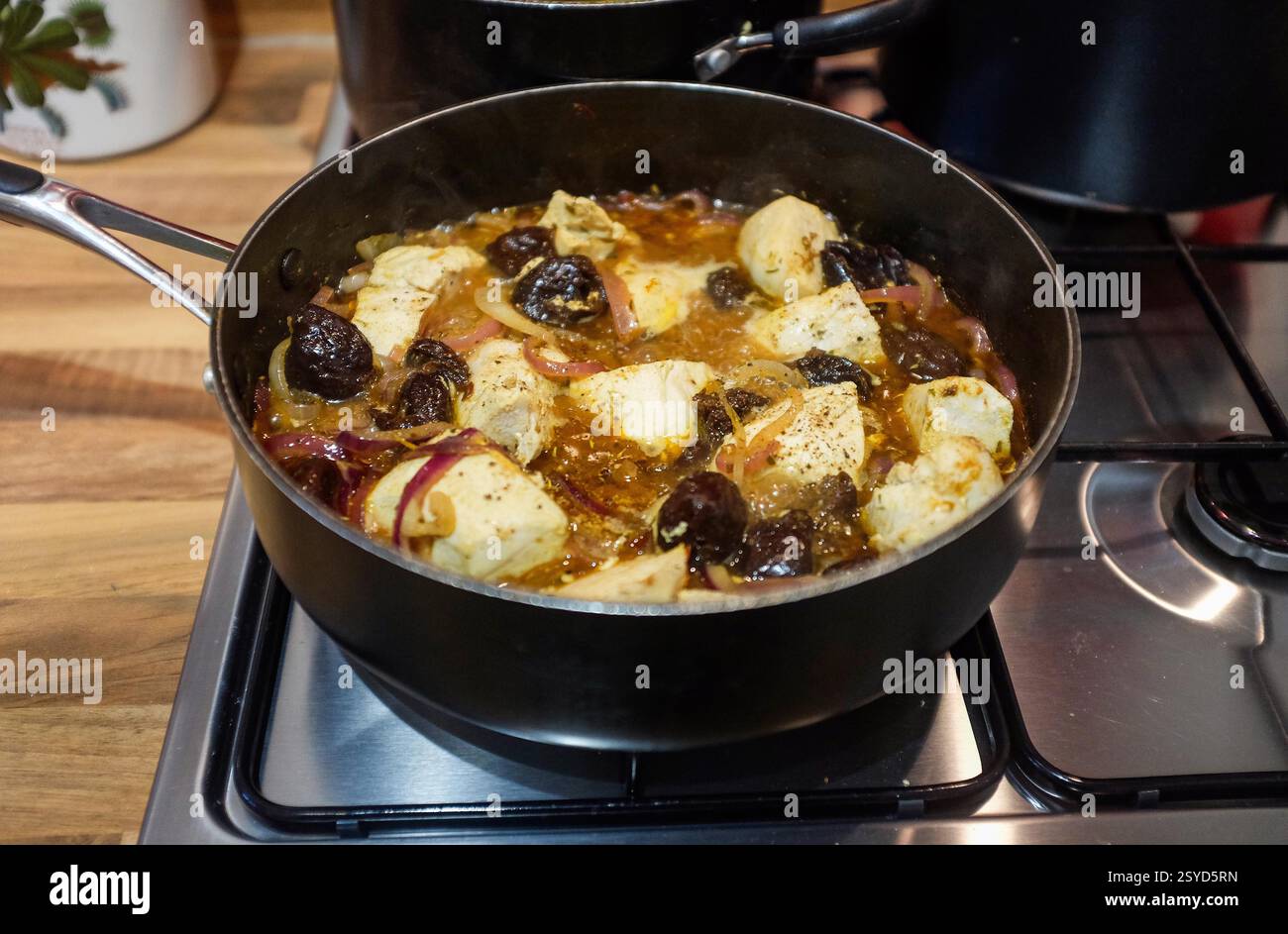 Es wird eine griechische Mahlzeit mit Hühnchen und Pflaumen zubereitet Stockfoto