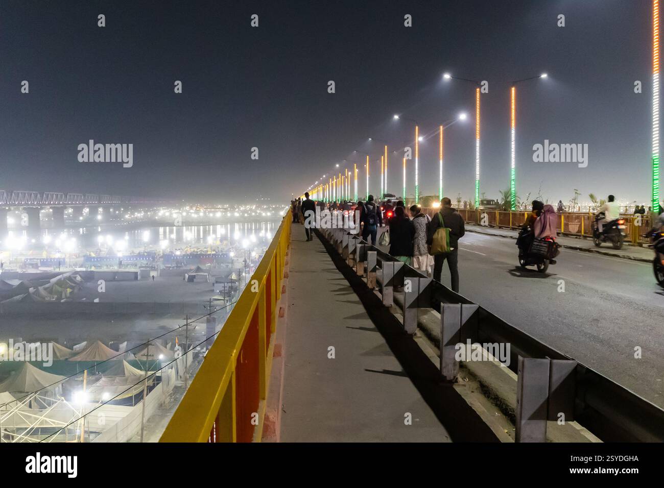 Menschen, die eine Straßenbrücke überqueren, mit temporären Lagern beim Mahakumbh-Festival in der Nacht werden Bilder im mahakumbh mela prayagraj uttar pradesh indien am Februar aufgenommen Stockfoto