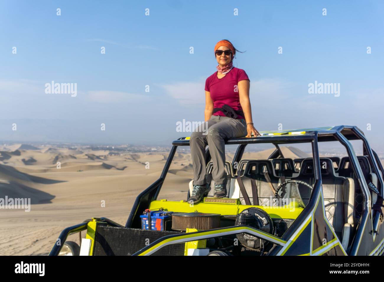 Eine Frau sitzt auf einem Buggy in der Huacachina Oase in Ica Peru, umgeben von Sanddünen und Palmen Stockfoto