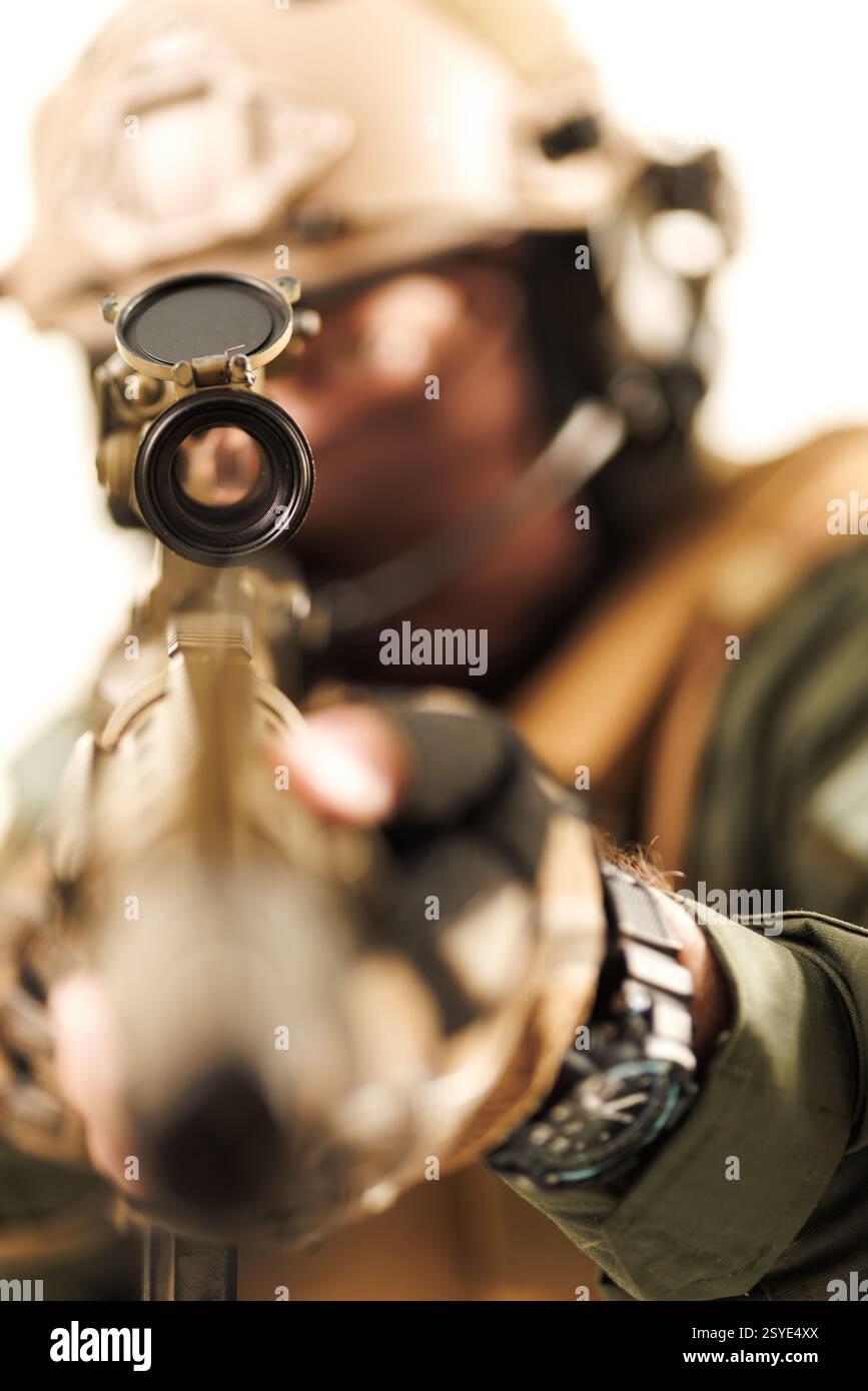 Fokussierter Soldat in Militäruniform, der mit Präzision durch ein mit Oszilloskop ausgestattetes Gewehr zielt. Demonstriert Konzepte der militärischen Ausbildung, des Kampfes Stockfoto